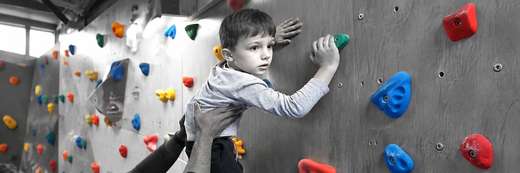 Child on an indoor climbing wall, supported by an adult, receiving NDIS paediatric allied health at Global Rehabilitation Service